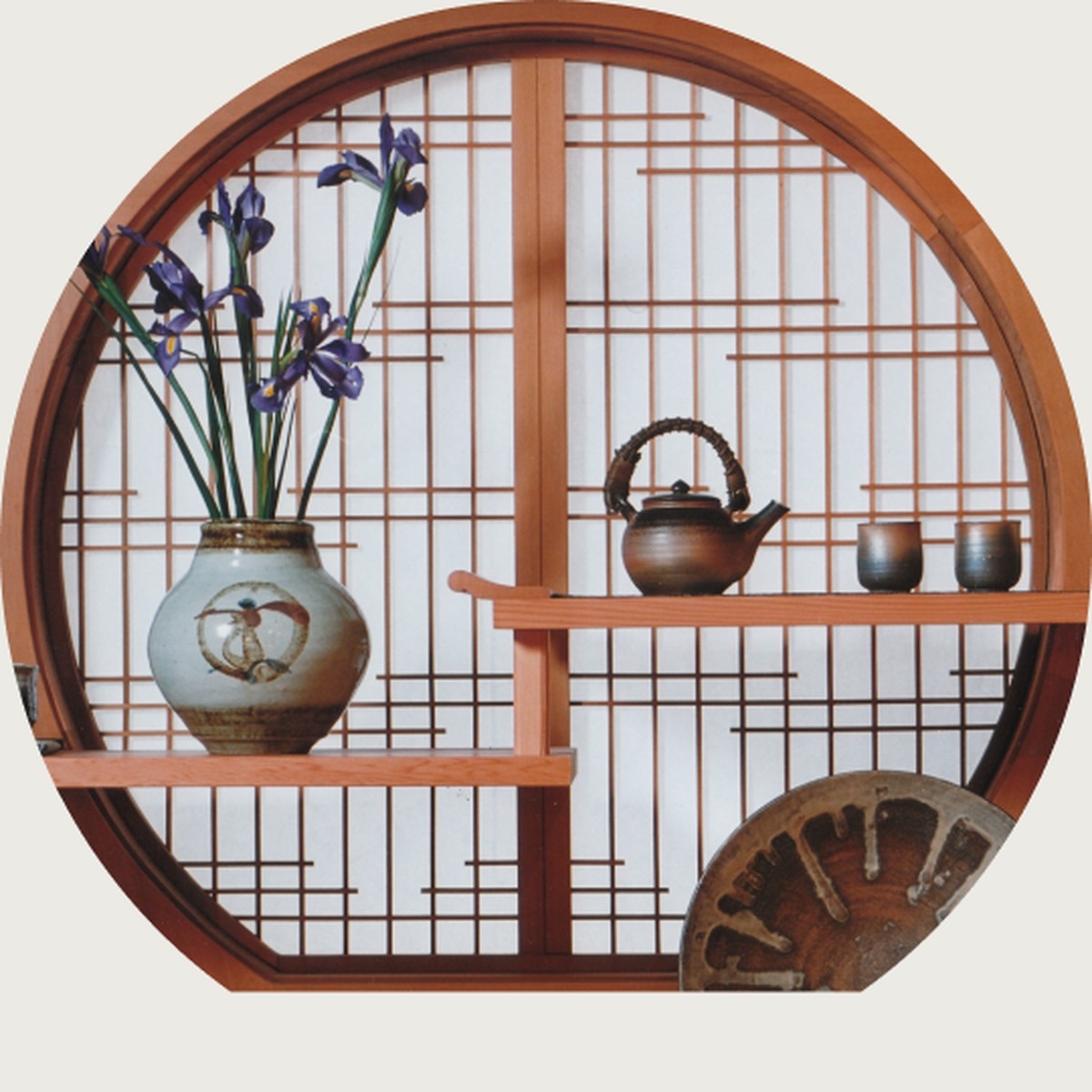 Circular shoji window framing a Japanese interior with a tea set and iris